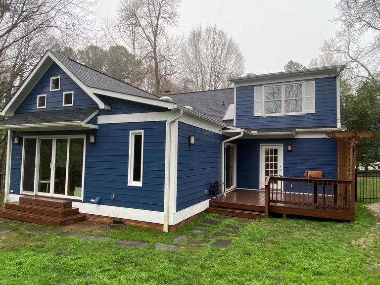 Navy blue siding and white trim on a home with a rear deck