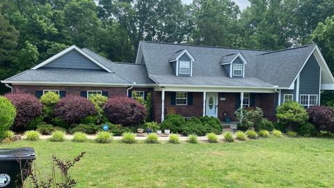 Single-story brick home with a gray shingle roof and landscaped front yard