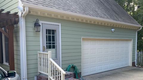 Sage green lap siding and white trim beside a two-car garage