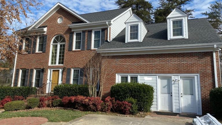 Red brick two-story home with white dormers and a yellow front door