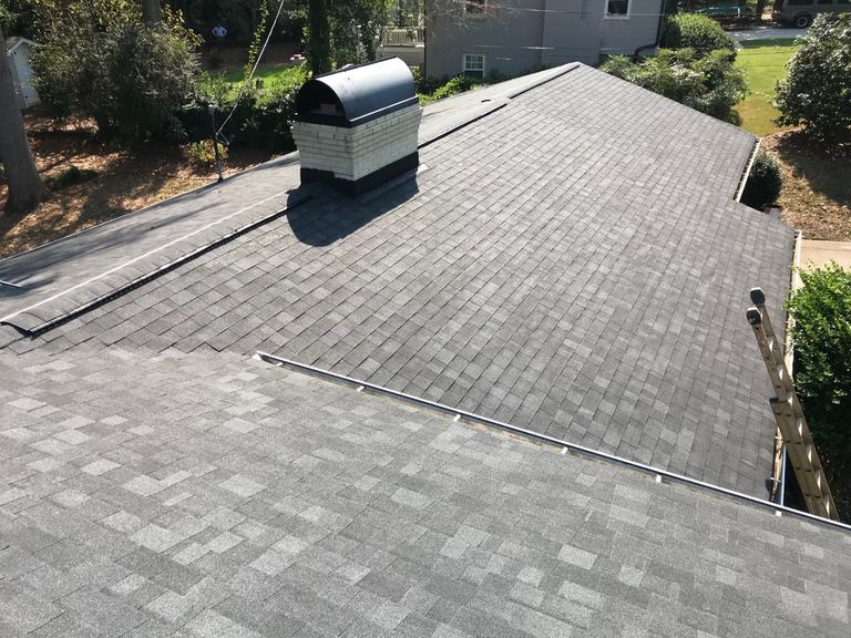 Aerial view of a newly shingled roof with a metal chimney cap