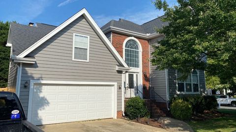 Two-story home combining tan siding and brick with a white garage door