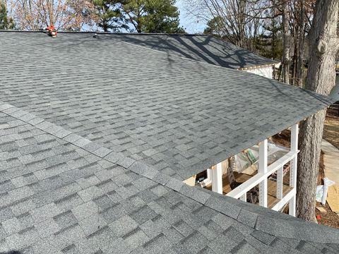 Gray architectural shingles part-way through installation on a steep roof