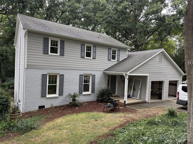 A two-story home clad in Pearl Gray HardiePlank lap siding with white window trim, charcoal shutters and a matching side-entry garage wing.