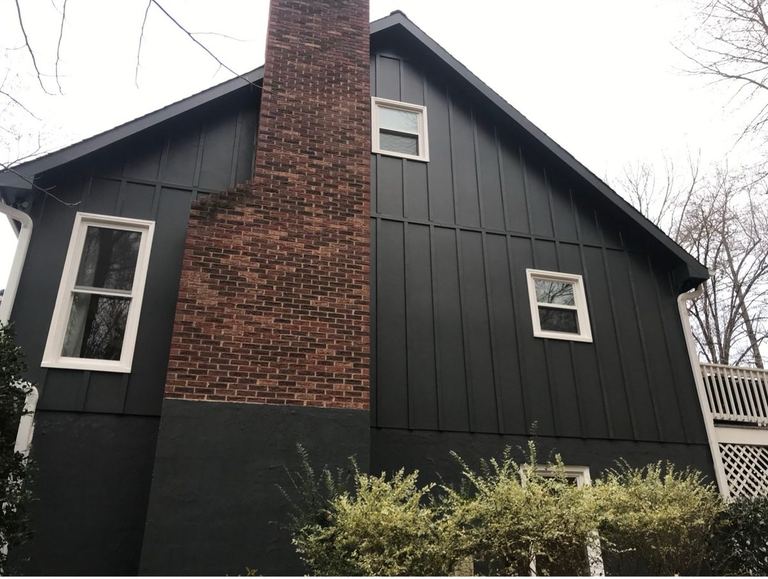 The gable end of a home in Iron Gray vertical HardiePlank running up against its original red brick chimney.